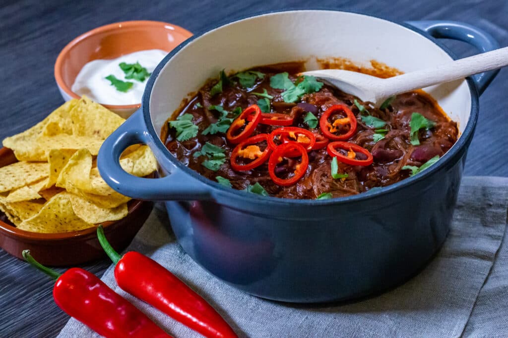 Beef breast with chili in a pot, with nachos and red chllis