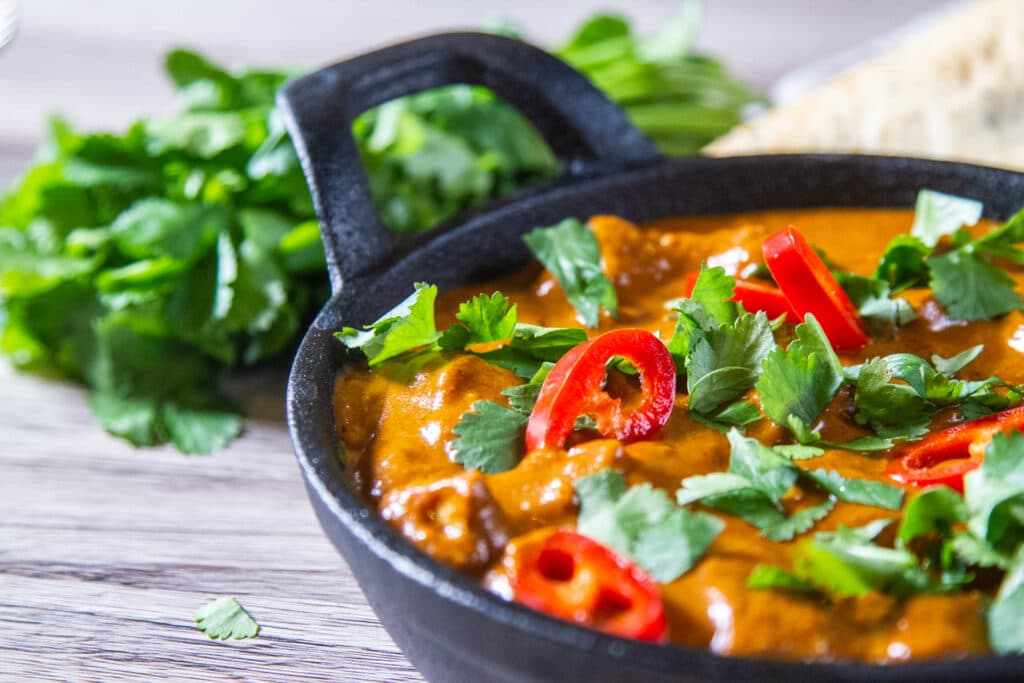 Closeup of Slow Cooker Butter Chicken, with coriander and fresh red chilli