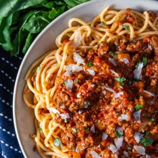 Overhead view of Slow Cooker Bolognese with spaghetti, basil and parmesan.