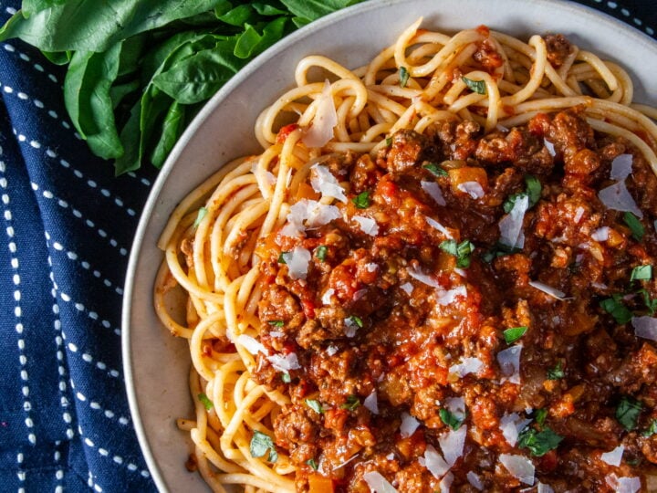 Overhead view of Slow Cooker Bolognese with spaghetti, basil and parmesan.