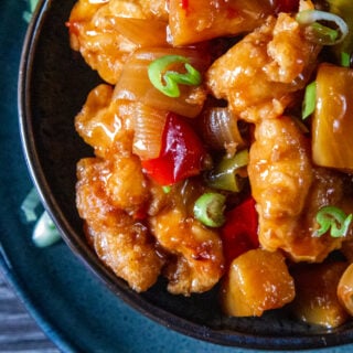 Overhead view of Slow Cooker Sweet and Sour Chicken in a bowl with spring onion garnish.