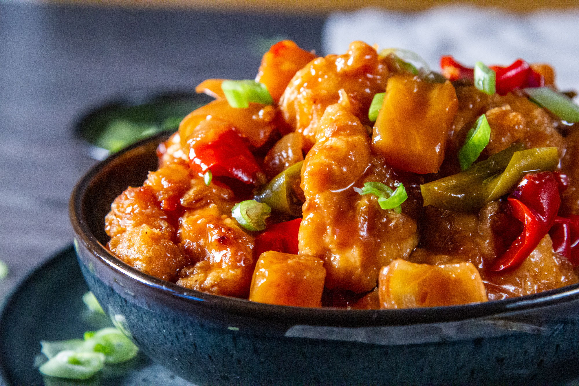 Aerial view of Slow Cooker Sweet and Sour Chicken in a bowl with a side of scallion and chopsticks.