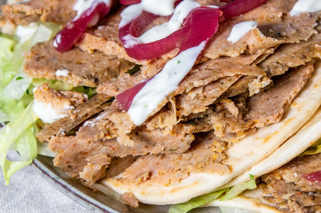Slow Cooker Lamb Kebab meat sliced and drizzled with garlic sauce.