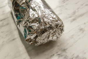 Image to show Slow Cooker Doner Kebab being wrapped in foil ready for cooking.