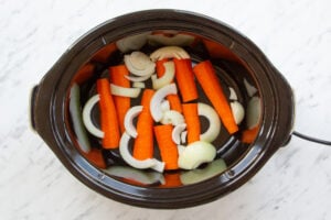 Image of carrot and onion trivet in pot ready to cook crockpot turkey crown.
