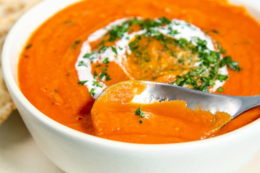 Close up image of a spoon in a bowl of Crockpot Tomato Soup. 