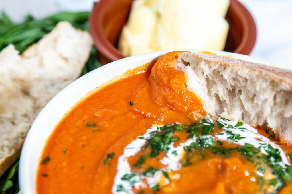 Close up image of a bowl of Slow Cooker Tomato Soup and crusty white bread.