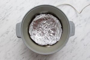 Picture of a slow cooker lined with foil.