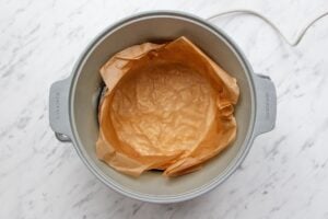 Picture of a slow cooker lined with baking parchment before baking a cake.