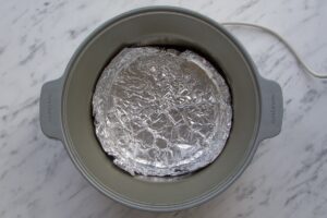 Image to show foil lining slow cooker pot before baking a cake.