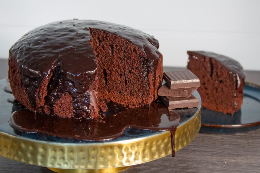 Picture of Slow Cooker Chocolate cake with chocolate icing. The cake has been cut and a slice is presented on a plate.