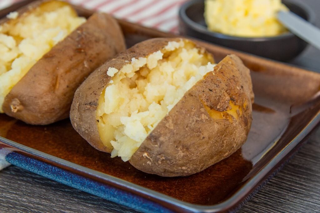 Image of jacket potatoes cooked in the slow cooker. The skins are crispy and the centre of the potato is fluffy and white.