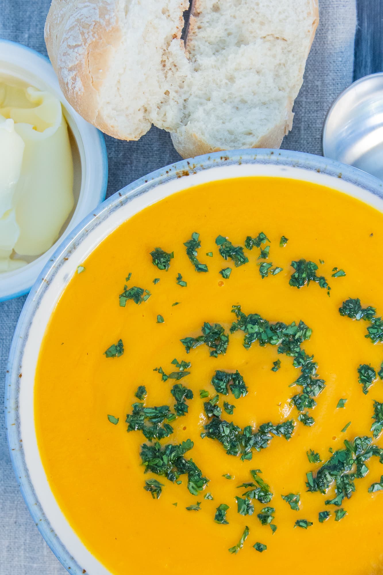 Overhead view of Crockpot Carrot and Coriander soup served with bread and butter.