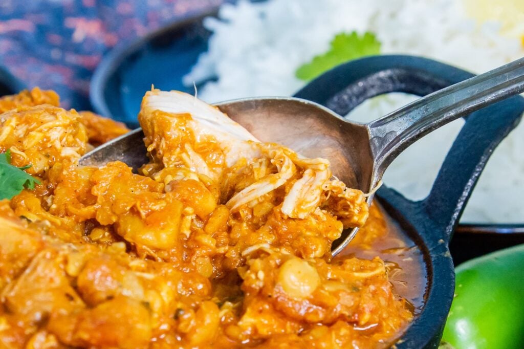 A bowl of Slow Cooker Chicken Dhansak, a serving spoon is in the bowl.