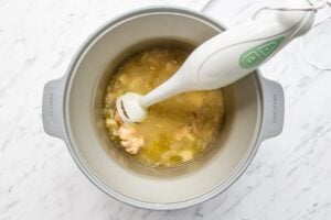 Picture of blending Slow Cooker Chicken Soup in the pot with a hand held blender.